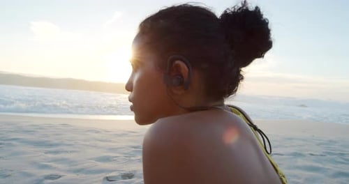 Fit, sporty and active female removing her earphones after a workout at the beach