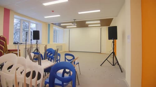 Chairs Pile Loudspeakers and Empty Screen in Conference Hall