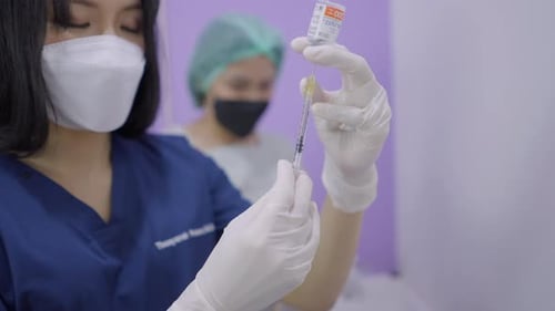 Thai Doctor Using Syringe to Extract Solution From Vial in Beauty Care Procedure
