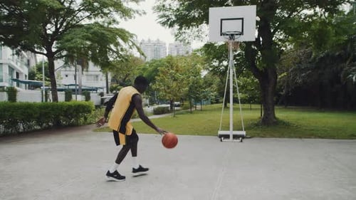 Young Adult Man Playing Basketball Outdoors