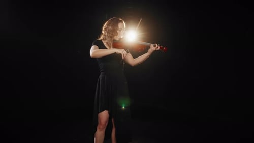 Elegant Woman Plays Violin in Dramatic Lighting