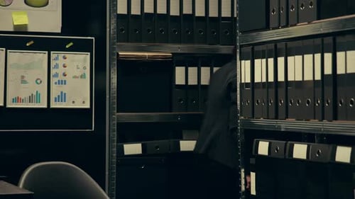 Young Adult Reviews Documents at Night in Office