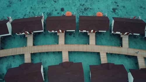 Vídeo com drone de cima para baixo de um resort tropical nas Maldivas, lagoa azul, clima ensolarado, sombra turquesa