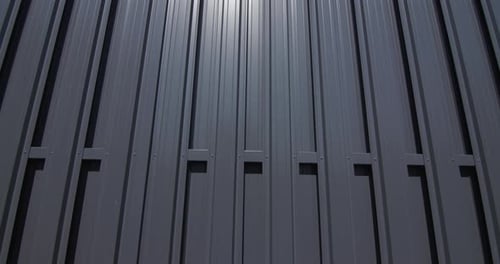 Metal Fence Reflects Sunlight With Blue Sky Overhead