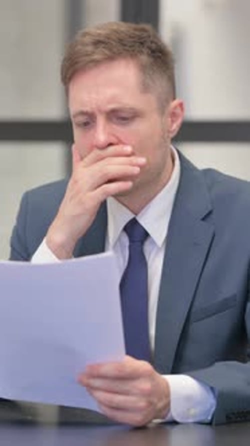 Worried Man Reading Documents in Office Setting