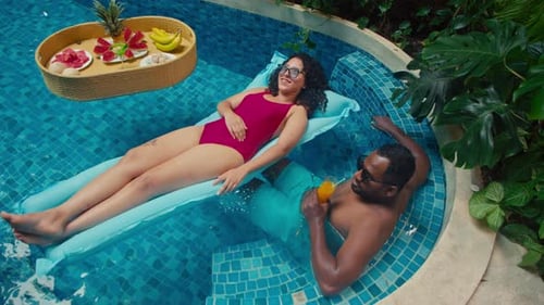 Happy Diverse Couple Chilling Out in Swimming Pool at Holiday Resort