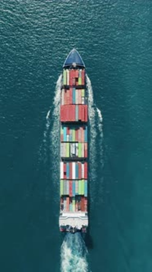 Capture a Vertical Video of a Cargo Ship with Colorful Containers at Sea From an Aerial Perspective