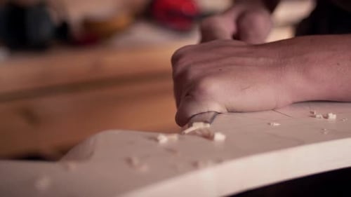Woodworker Shaping Wood with Chisel in Workshop