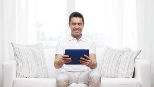 Smiling man using a tablet on the couch