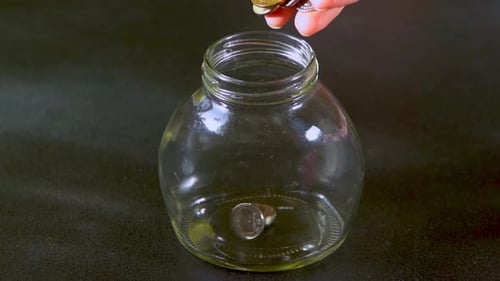 Coins Falling Into A Glass Jar For Savings