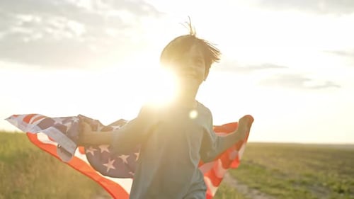 Boy Runs with American Flag in Field at Sunrise