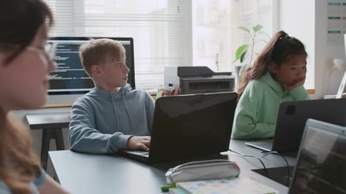 Grupo de niños concentrados que usan computadoras portátiles durante la lección de programación
