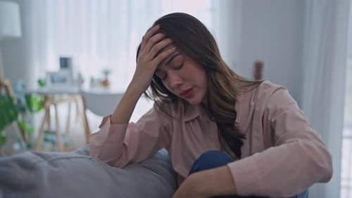 Young Woman Sitting on Couch Looking Distressed