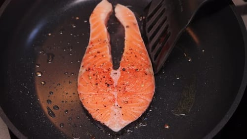 Salmon steak sizzles in hot pan