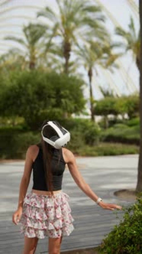 A Young Woman is Outside in a Sunny Park Immersed in a Virtual Reality Experience