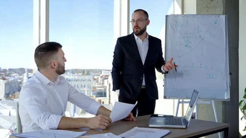 Male colleagues cooperating in office. Businessmen coworkers discussing together at workplace busine