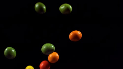 Colorful Candies Falling Against Black Background