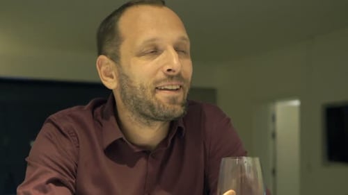 Man drinking red wine indoors at a table
