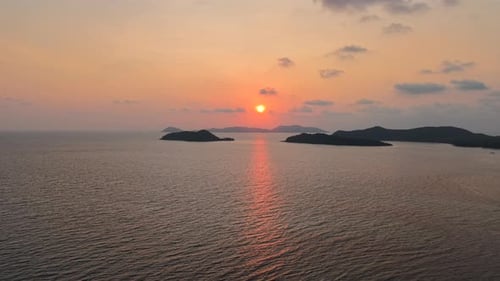 Sonnenuntergang über dem ruhigen tropischen Meer zwischen den Silhouetten ferner Inseln, goldenes Lichtgemälde, Himmel