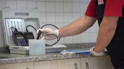 Un homme en gants blancs vérifie la pureté de l'eau dans un laboratoire et enregistre les données