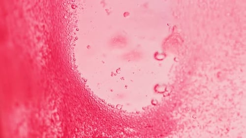 macro shot of bright red water with many sparkling bubbles leaving a little spot without bubbles