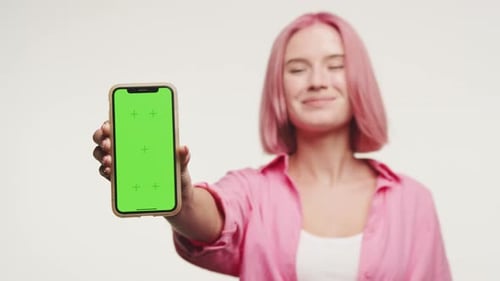 Smiling Woman Presenting Smartphone with Green Screen