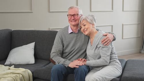 Smiling Senior Couple Sitting Affectionately on Couch