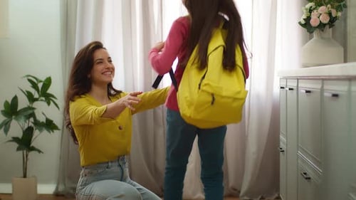 Happy Mother Hugging Daughter With Backpack Indoors