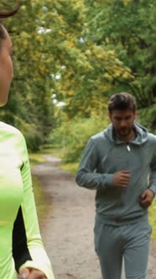 Vertical of Young Lady Runner Looks Back to His Partner While Running and Winning Race in Park