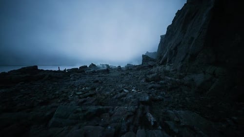 Desolate Rocky Shoreline Under Cloudy Sky with Tranquil Waters