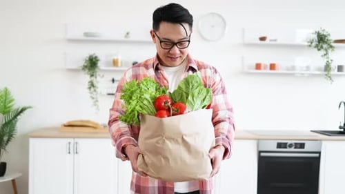 Smiling Man Holding Groceries in Modern Kitchen