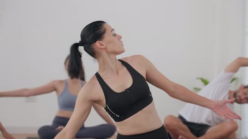 Group Yoga Class in a Bright Studio with Instructor Giving Guidance