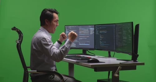 Happy Man Developer Celebrating While Write Code With Multiple Computer Screens In Green Screen
