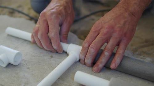 Hands Connecting White Plastic Pipes in a Home