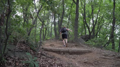 European tourist hiker walks up the trail path sweat and tired, forest frees background low angle vi