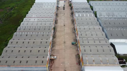 Aerial view of a goods distribution warehouse lined up with goods trucks parked in front of the ware