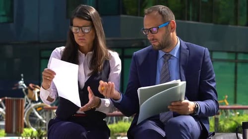 Upset Businessman with Businesswoman Working with Documents in the City Analyzing