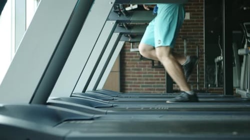 Process of Running on Treadmill By Athletic Young Man in Gym Side View