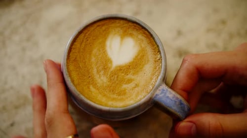 Female Hands Moving a Coffee Cup Drawing on Coffee Top View