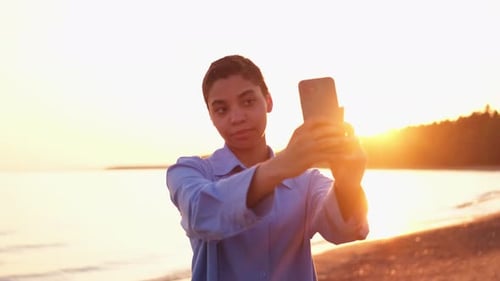 Young Woman Taking Selfie at Beach at Sunset