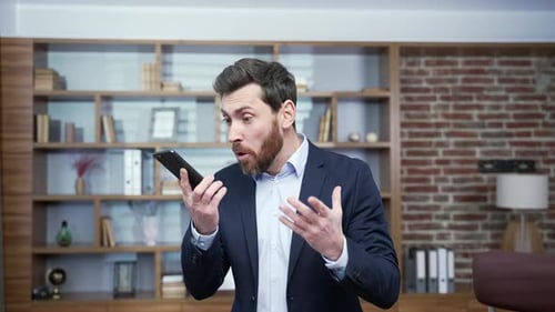 Irritated arguing business man yelling shouting into smartphone gadget microphone at office Angry