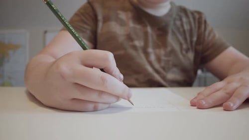 Child Writes Letters on Paper at Desk