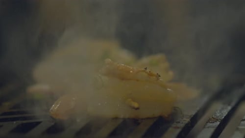 Pouring a marinade sauce over a skewer of shrimp being flame grilled - isolated close up