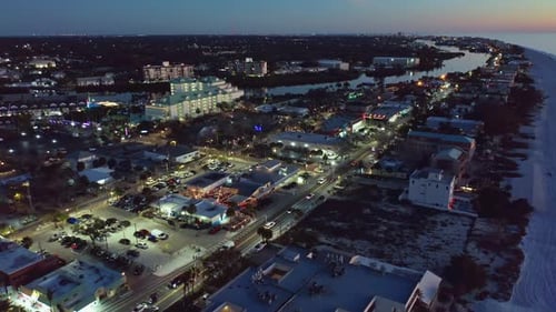 Coastal cityscape along beach at dusk with illuminated streets