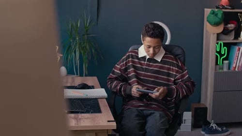 Teen Boy Plays on a Mobile Gaming Device