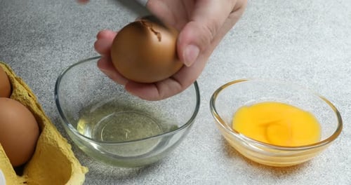 Egg being separated into bowls on counter