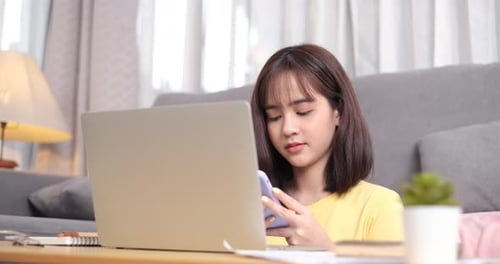 Woman Using Smartphone and Laptop at Home
