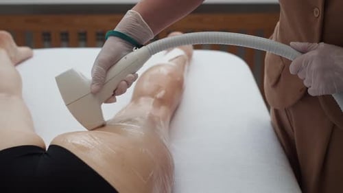 A Beautician Performs Laser Hair Removal on Women's Legs