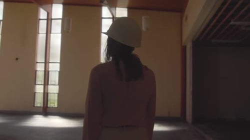 Arquitecta que camina con un casco blanco entrando en una habitación enorme durante una observación