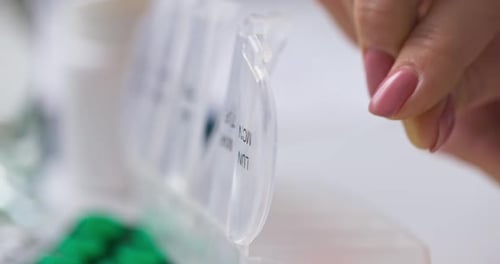 Woman Hand Putting Pills Into Open Pill Organizer or Plastic Pillbox